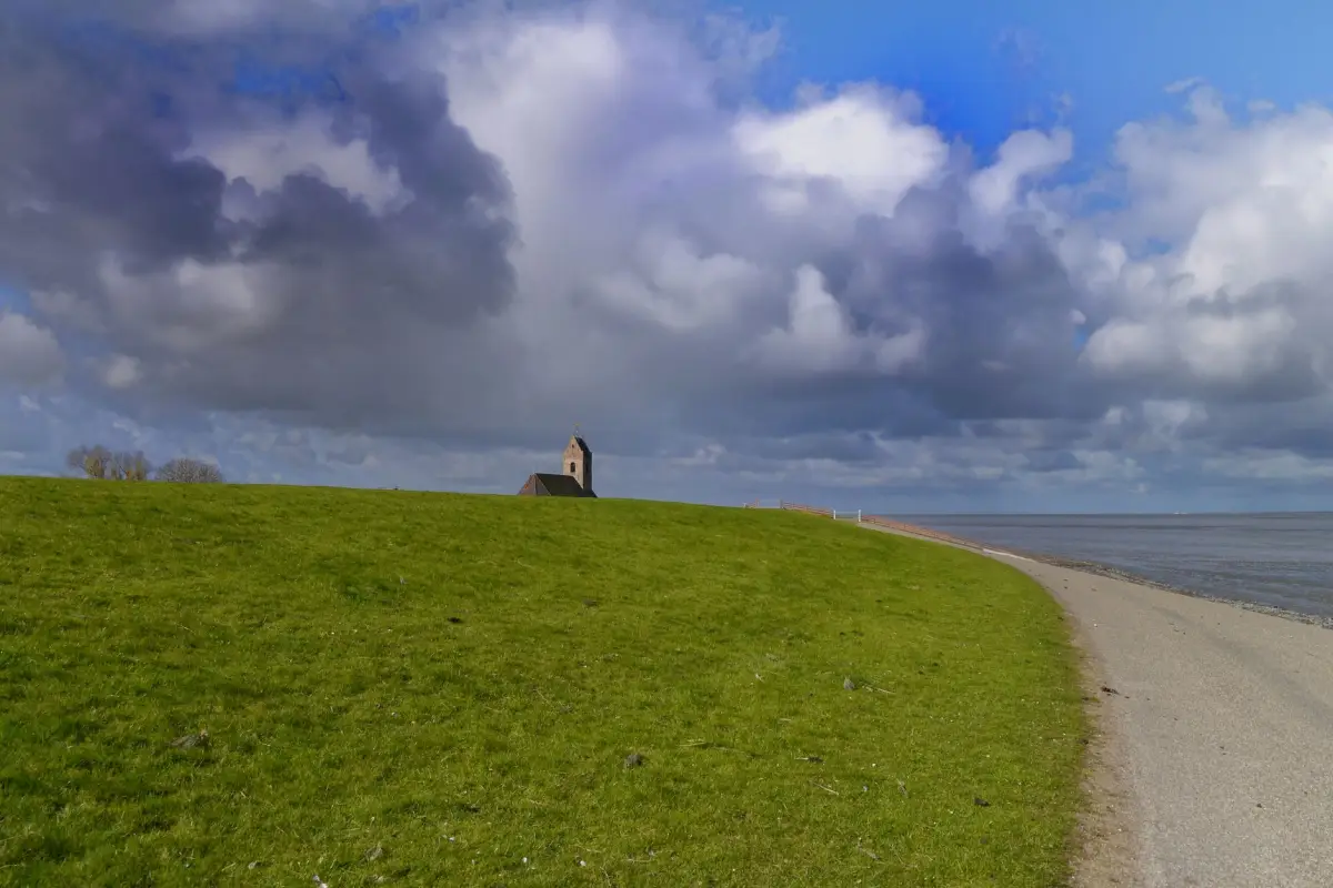 Dijk met wolkenlucht in het Zeeuwse landschap