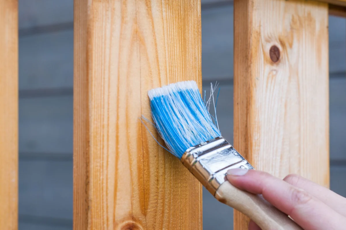 Kwast met verf op houten boeidelen